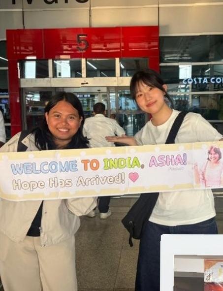 Welcome to India, Asha banner at the airport
